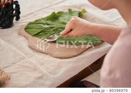 Girl holding spoon and touching to the fresh leaf laying at the clay 80396970
