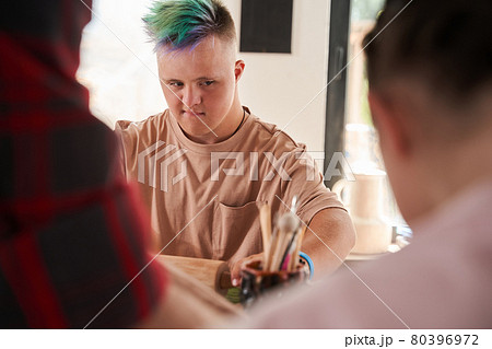 Man with down syndrome holding rolling pin and looking at his girlfriend 80396972