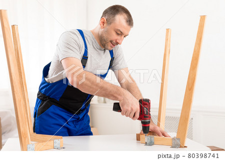 Repairman In Blue Uniform Fixing Table With Electric Drill Indoors Repairman In Blue Uniform Fixing Table With Electric Drill Indoors 80398741