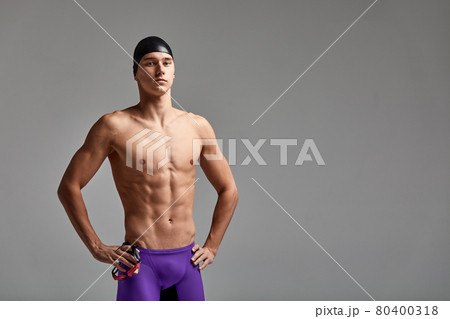 Portrait of a swimmer in a cap and mask, half-length portrait, young athlete swimmer wearing a cap and mask for swimming, copies of space, gray background 80400318