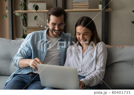 Laughing couple enjoy funny internet content while sit on sofa 80401735