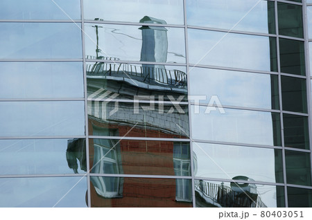 Reflection of clouds, blue sky and the other buildings in the glass windows of office building 80403051