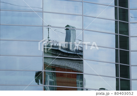 Reflection of clouds, blue sky and the other buildings in the glass windows of office building 80403052