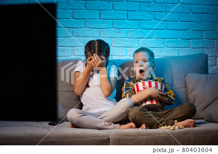 two children with remote control watching TV 80403604