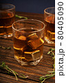 Glass with whiskey and metal ice cubes on a wooden table close-up. 80405090