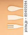 Three wooden spatulas for the kitchen on a light peach background. Bamboo kitchen tools. 80405094