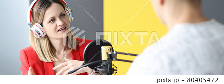 Young woman with headphones interviewing man on radio Young woman with headphones interviewing man on radio 80405472