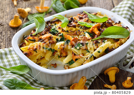 Chanterelle pasta casserole with spinach leaves and cheese served hot from the oven 80405829