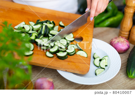 Female hands cuts vegetables on cutting board Female hands cuts vegetables on cutting board 80410007
