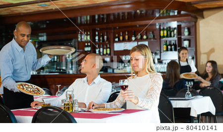 Latino waiter brought delicious pizza to restaurant guests 80410141
