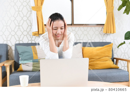 パソコンの前で頭を抱える若い女性 80410665