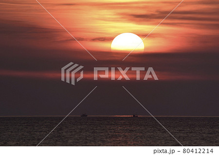 夏の北海道江差町で沈んでゆく夕陽と漁り火を照らす前のイカ釣り漁船の風景を撮影 80412214