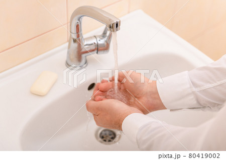 hand washing with soap or gel under running water in the washbasin, cleanliness and hygiene, men's hands dressed in a white shirt hand washing with soap or gel under running water in the washbasin, cleanliness and hygiene, men's hands dressed in a white shirt 80419002