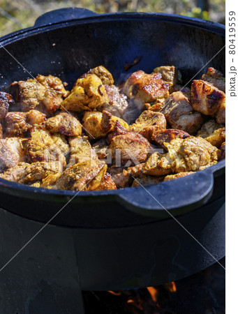 The meat is fried in a cast-iron cauldron over an open-air fire The meat is fried in a cast-iron cauldron over an open-air fire 80419559