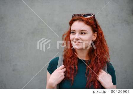Portrait of young woman standing outdoors against gray background. Copy space. Portrait of young woman standing outdoors against gray background. Copy space. 80420902