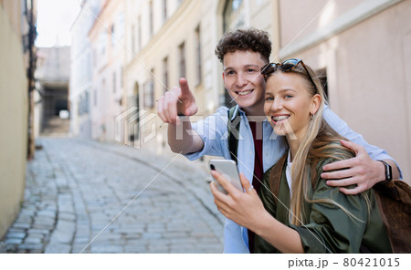 Young couple travelers using smartphone in city on holiday, sightseeing. 80421015