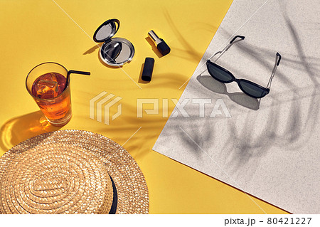 Straw beach woman's hat and sun glasses, top view yellow and white paper background with shadow from a palm leaf. Straw beach woman's hat and sun glasses, top view yellow and white paper background with shadow from a palm leaf. 80421227