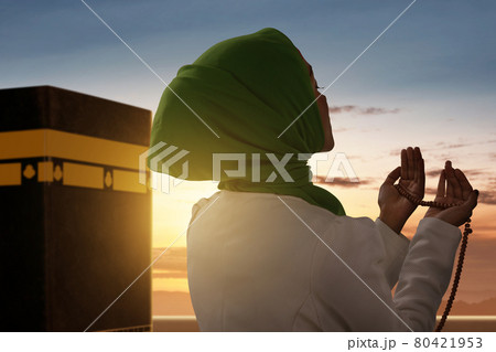 Rear view of Asian Muslim woman in a veil standing and praying with prayer beads 80421953