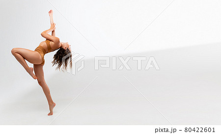 One young beautiful tanned caucasian woman in mustard underwear posing over white background. Flyer 80422601