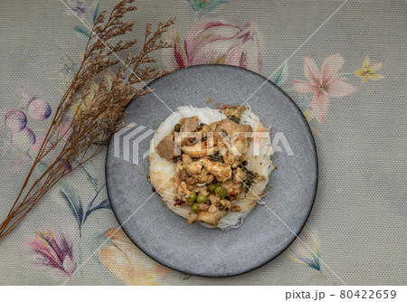 Green curry with chicken (Kaeng kheow hwan with chicken) on top of soft rice noodle on ceramic plate. 80422659