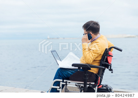 a man with disabilities in a wheelchair talking on a smartphone a man with disabilities in a wheelchair talking on a smartphone 80424987