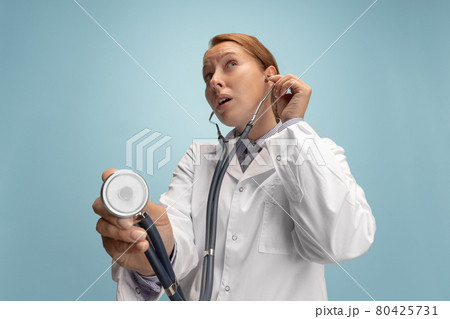 Close-up female doctor, therapeutic or medical advisor with stethoscope at work isolated over blue studio background. Concept of healthcare, care medicine and humor Close-up female doctor, therapeutic or medical advisor with stethoscope at work isolated over blue studio background. Concept of healthcare, care medicine and humor 80425731