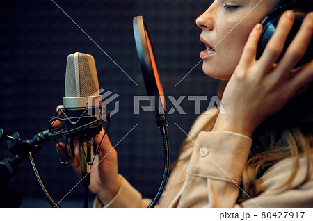 Female performer at micriphone, recording studio 80427917