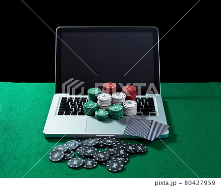 Casino chips and cards on keyboard notebook at green table. 80427959