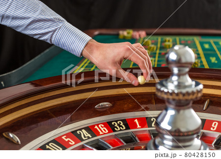 Roulette wheel and croupier hand with white ball in casino Roulette wheel and croupier hand with white ball in casino 80428150
