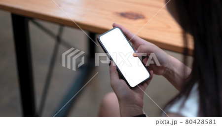 Woman hand holding smartphone at coffee cafe shop. Blank screen mobile phone for graphic display montage. Woman hand holding smartphone at coffee cafe shop. Blank screen mobile phone for graphic display montage. 80428581