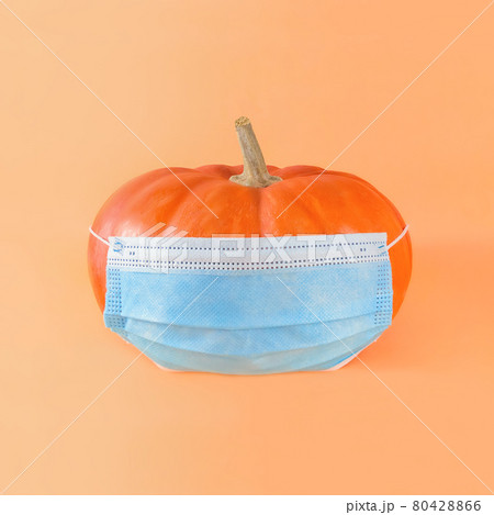 Orange pumpkin in medical mask on a beige background. Orange pumpkin in medical mask on a beige background. 80428866