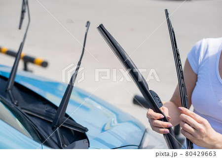 Faceless woman changing car windshield wipers. 80429663