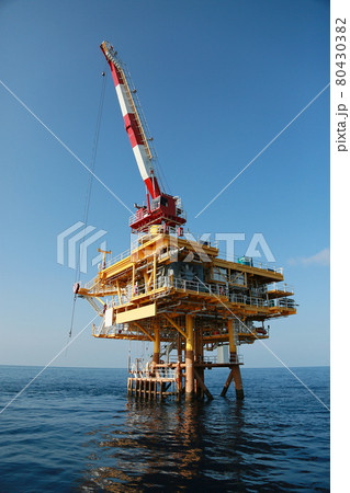 Oil and gas platform standing in the gulf or offshore and operation by technician. Crane moving any cargo or tools basket from supply boat to the platform. Heavy lift was moving by crane technician. 80430382