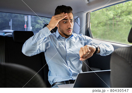 Worried arab businessman looking at watch while sitting in car Worried arab businessman looking at watch while sitting in car 80430547