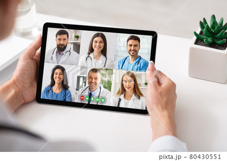 Physician Making Group Video Call With Colleagues Using Tablet Indoor Physician Making Group Video Call With Colleagues Using Tablet Indoor 80430551
