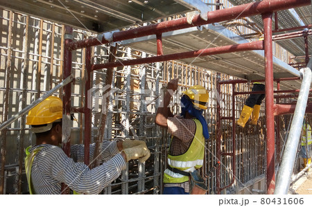 KUALA LUMPUR, MALAYSIA -JANUARY 14, 2017: Construction workers fabricating steel reinforcement bar at the construction site. The reinforcement bar was tied together using tiny wire. KUALA LUMPUR, MALAYSIA -JANUARY 14, 2017: Construction workers fabricating steel reinforcement bar at the construction site. The reinforcement bar was tied together using tiny wire. 80431606