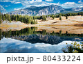 A beautiful field with a lake in front and mountains in the back. 80433224