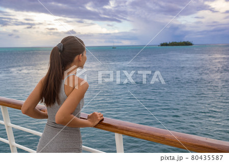 Luxury cruise vacation woman looking at French Polynesia motu island from boat deck at sunset. Elegant tourist relaxing at view of ocean scenery at dusk, relaxing outdoor. Sailing lifestyle holidays 80435587