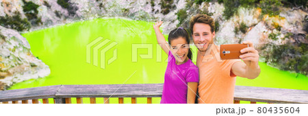New Zealand tourism travel destination people lifestyle. Banner panorama. Couple tourists taking selfie travel destination, Waiotapu. Active geothermal green pond, Rotorua, north island, Wai-O-Tapu. New Zealand tourism travel destination people lifestyle. Banner panorama. Couple tourists taking selfie travel destination, Waiotapu. Active geothermal green pond, Rotorua, north island, Wai-O-Tapu. 80435604