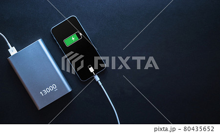 Charging power bank. Portable powerbank with white usb cable for charger mobile phone or smartphone battery. Modern technology concept in top view. Charging power bank. Portable powerbank with white usb cable for charger mobile phone or smartphone battery. Modern technology concept in top view. 80435652