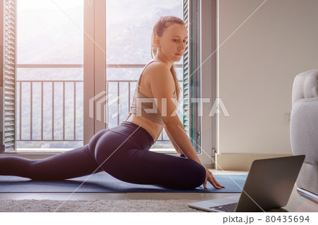 Fit woman stretching her legs in pigeon yoga pose Fit woman stretching her legs in pigeon yoga pose 80435694