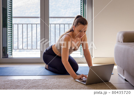 Young woman taking online fitness class at home 80435720