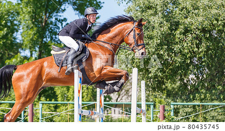 Young rider man jumping over the barrier 80435745