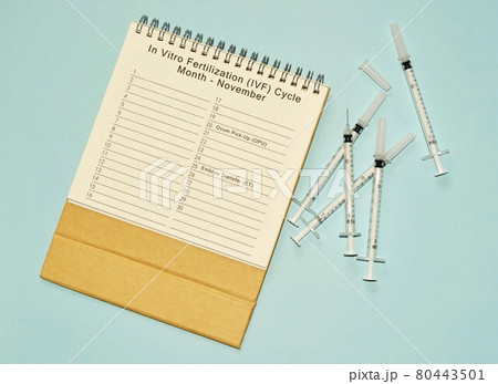 November IVF cycle calendar and disposable injection syringe on blue background 80443501