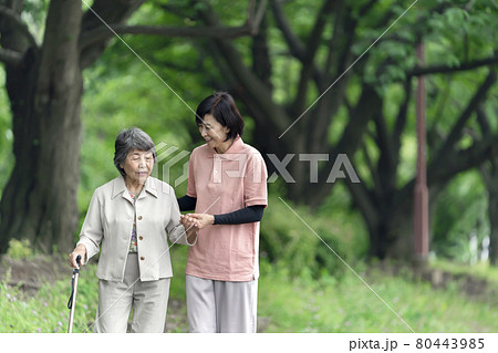 公園で散歩するシニア女性と介護士 80443985