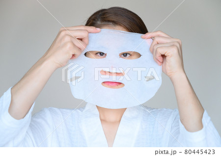 Portrait of young woman holding facial mask befor applying to enhance her skin and looking to camera. Facial mask is a creamy or thick pasted mask applied to clean or smoothen the face. Portrait of young woman holding facial mask befor applying to enhance her skin and looking to camera. Facial mask is a creamy or thick pasted mask applied to clean or smoothen the face. 80445423
