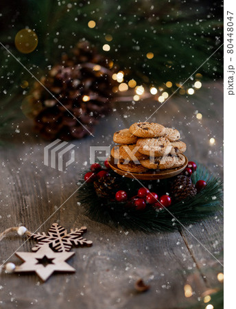Christmas cookies in plate, festive tree and pine cones, bokeh light. Christmas sweets. Sugar powder poured onto the cookies 80448047