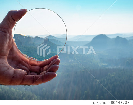 Crystal glass ball in a man's hand. The morning misty hilly landscape Crystal glass ball in a man's hand. The morning misty hilly landscape 80448283