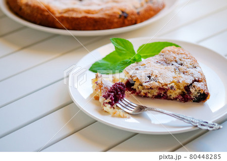 Piece of homemade simple pie with fresh red raspberries and black mulberry on a light background. Summer berry dessert. close up 80448285