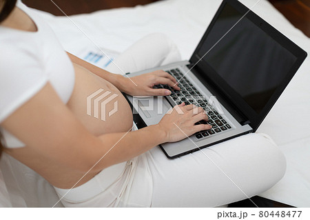 Pregnant business woman sitting and working on the laptop with sale report,tablet,books and sticky note at home,Pregnant of businesswoman typing on laptop,Business and Pregnancy Concept 80448477